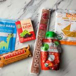 prepackaged snacks shown from left to right: Dino Bar, Raisins, Larabar, Goodpop, Applesauce, Bitsy's Crackers
